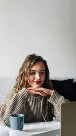 Portrait of smiling young woman sitting against white background