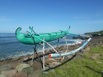 Ship moored on beach against blue sky