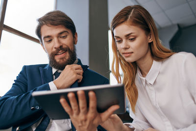 Young couple looking away while using mobile phone