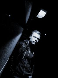 Portrait of man standing by wall at night