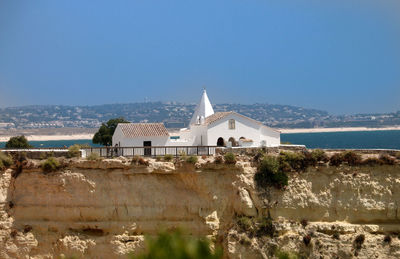 Buildings by sea against clear sky