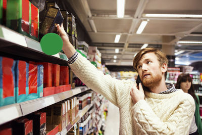 Man answering mobile phone while shopping at supermarket