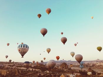 Hot air balloons flying over land against clear sky at sunset