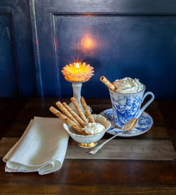 Gourmet hot chocolate and whip cream in a nautical china mug with cookies on a rustic table 