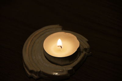 Close-up of lit candle in dark room