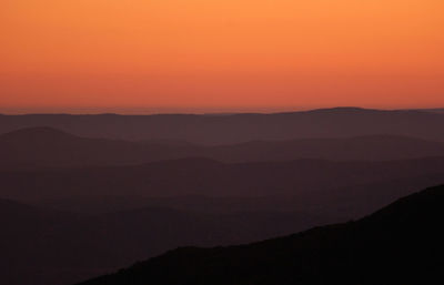 Scenic view of silhouette mountains against orange sky during sunset