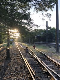 People walking on railroad track against sky