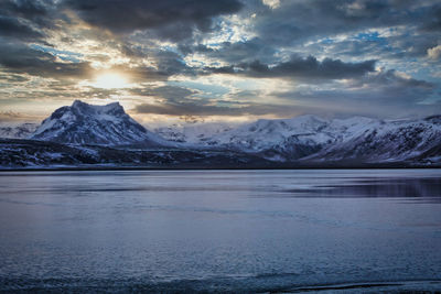 Scenic view of lake and snowcapped mountains against sky during sunset