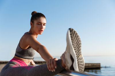 Woman exercising against clear blue sky