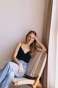 Full frame of woman sitting on a woven chair looking at camera 