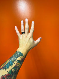 Close-up of human hand against orange background