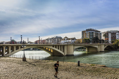 Bridge over river in city against sky