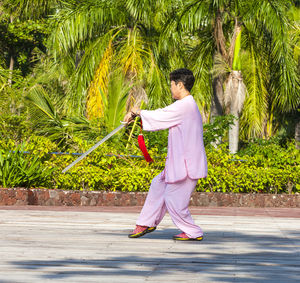 Side view of man holding umbrella standing on footpath