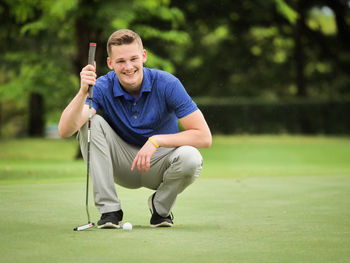 Portrait of smiling young man with golf club on course