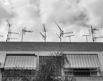 Low angle view of telephone pole on roof of building against sky