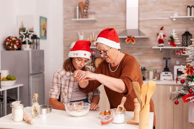 Grandmother making cookies with granddaughter at home