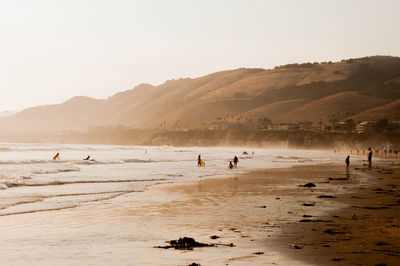 People on beach against clear sky