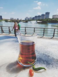 Close-up of drink on table by sea against sky