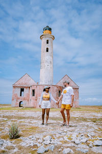 People on building by lighthouse against sky