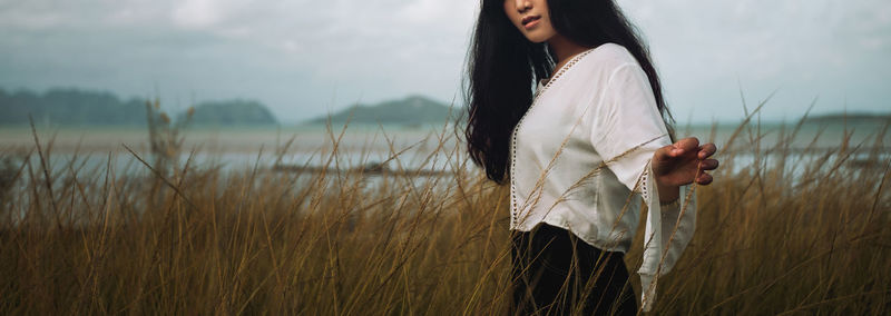 Asian long hair girl in white clothes enjoys life in nature coastal field.