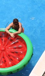 High angle view of man leaning on inflatable ring in swimming pool