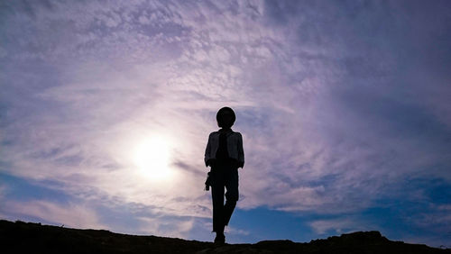 Rear view of silhouette man standing against sky during sunset