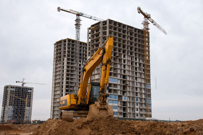 Low angle view of crane at construction site against sky