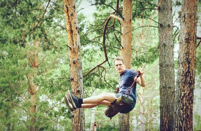 Portrait of man on swing in forest