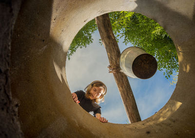 Low angle view of a kid looking into the  well
