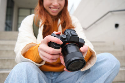 Midsection of woman holding camera