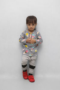 Portrait of cute boy standing against white background