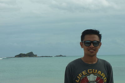 Portrait of young man standing against sea