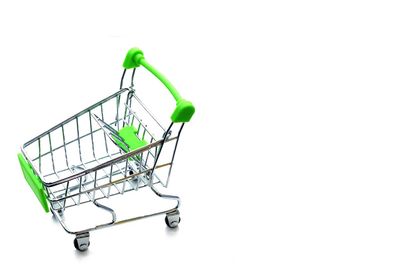 Close-up of miniature shopping cart over white background