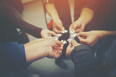 Cropped image of friends playing jigsaw puzzle