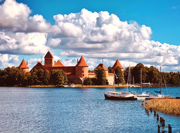 Buildings at waterfront against cloudy sky