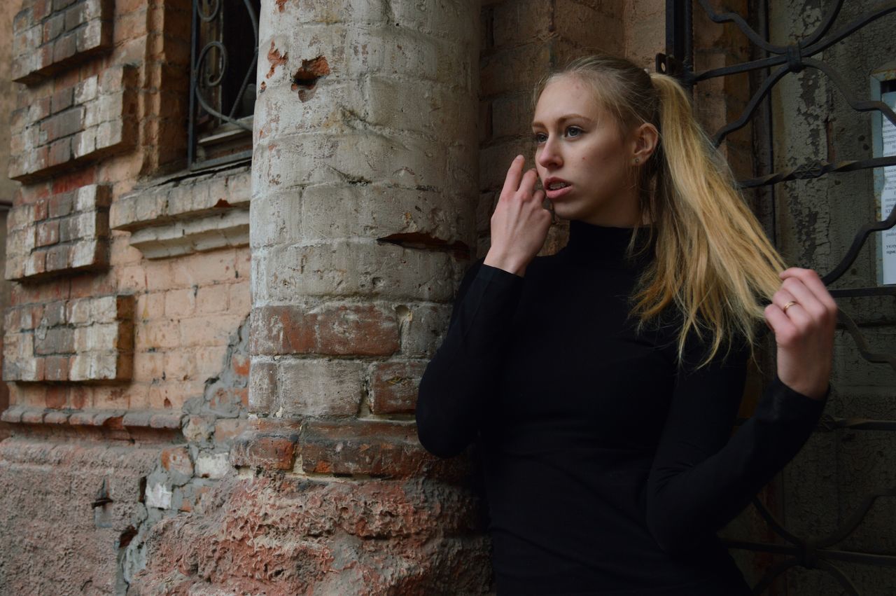 young adult, young women, one young woman only, blond hair, contemplation, beautiful woman, one person, only women, long hair, beauty, beautiful people, one woman only, brick wall, built structure, architecture, adults only, adult, real people, people, outdoors, day