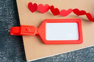 Close-up view of red heart shape decoration and label on clip board