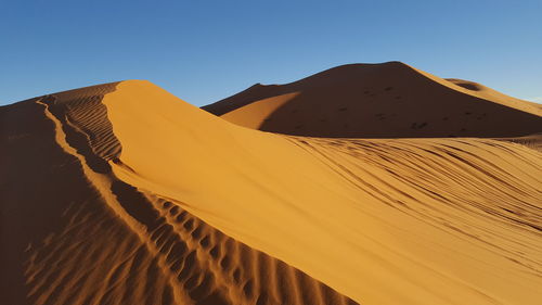 Low angle view of sand dunes against clear sky