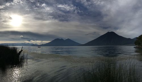 Scenic view of lake atitlan facing the volcano against sky during sunset