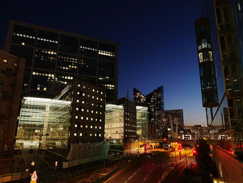 Illuminated city street and buildings against sky at night