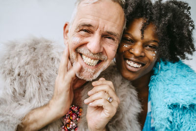 Portrait of smiling woman and gay man with shiny blusher on faces at home