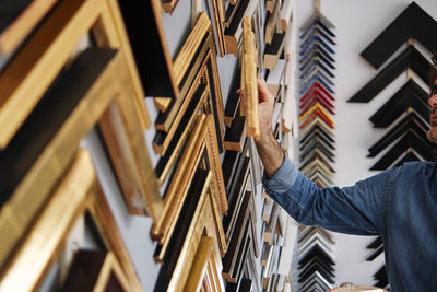 Craftsman removing picture frame from wall while working in store