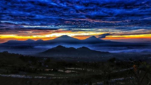 Scenic view of mountains against dramatic sky during sunset