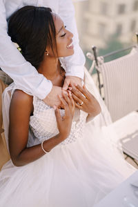 Smiling bride with groom embracing outdoors