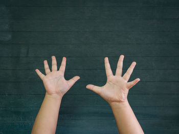 Cropped hands of person gesturing against wall