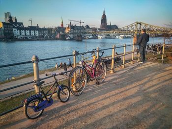 Bicycles parked by railing against river