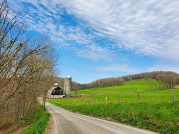 Road amidst field against sky