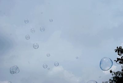 Low angle view of bubbles against blue sky