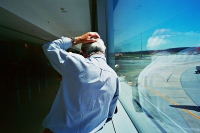 Rear view of man standing by window