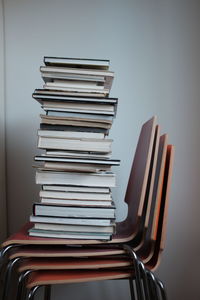 Stack of books on chair against wall